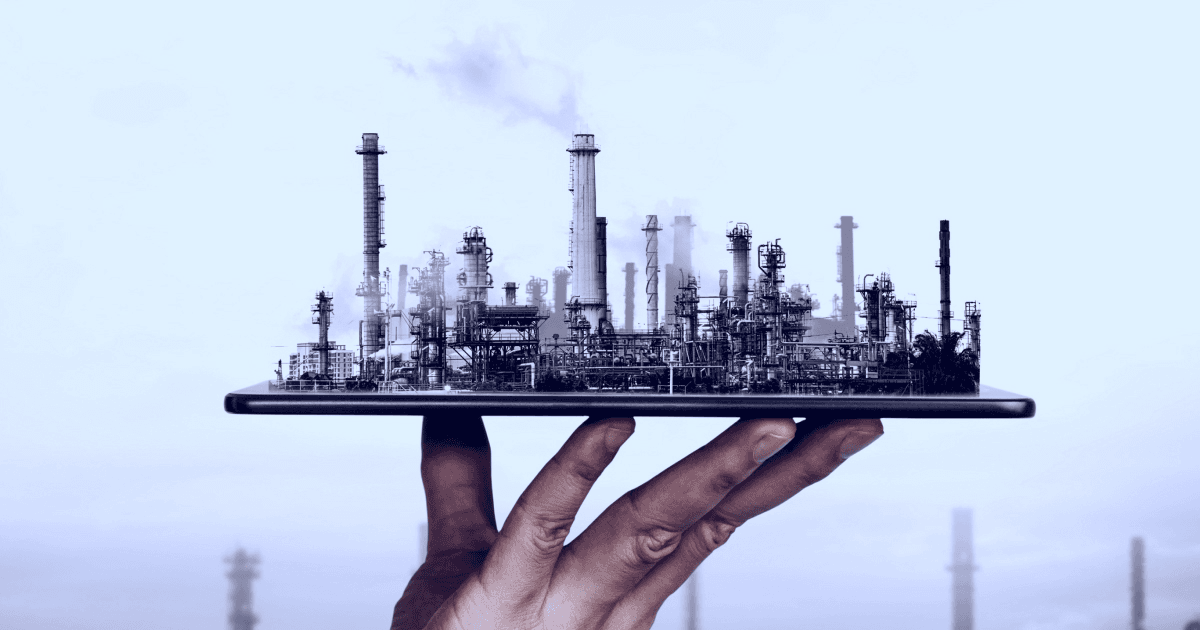 Fingertips holding a mobile phone from which industrial plant emerges