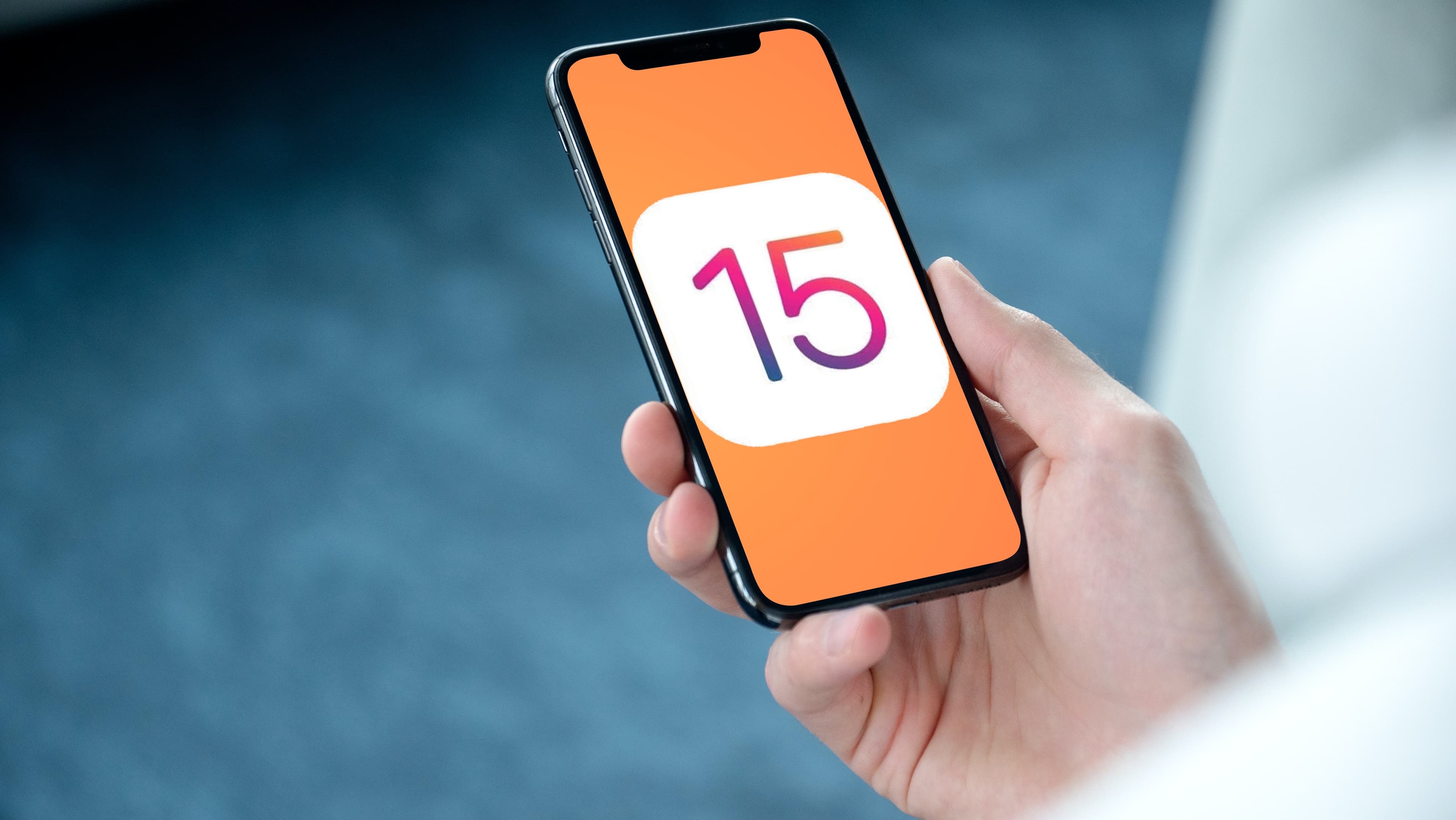 hand holding iPhone iOS 15 logo