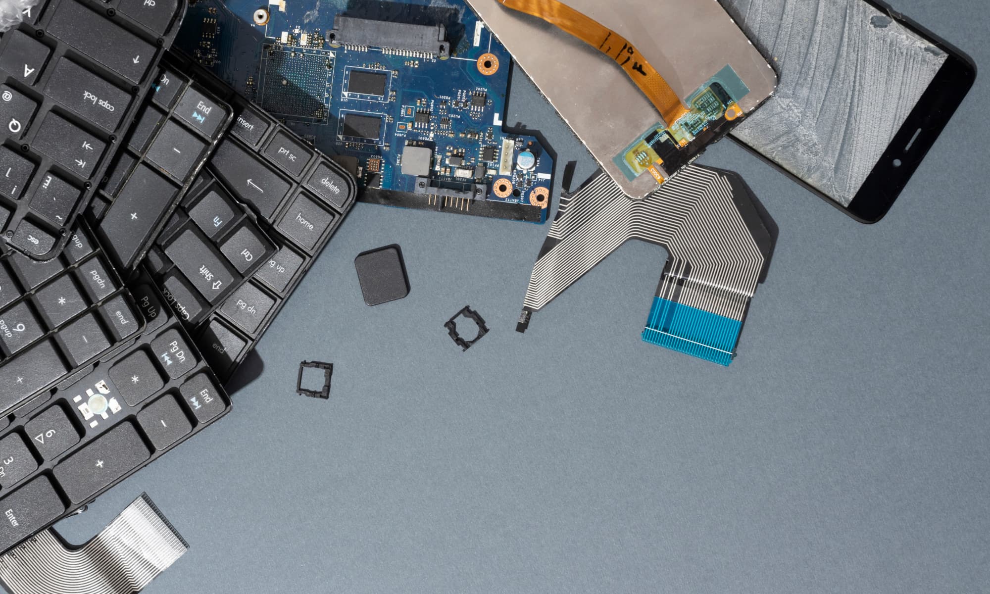 a selection of disassembled electronics including computer keyboards and smartphones