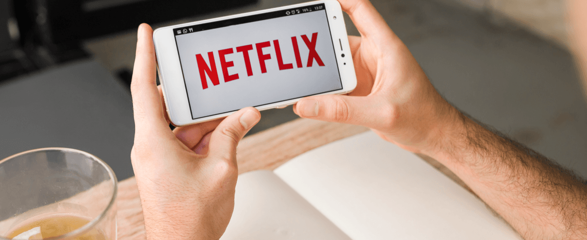 Man holding mobile phone and using it to watch netflix