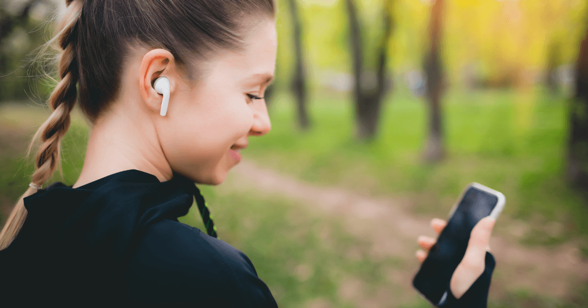 Girl wearing wireless earphones whilst walking with her mobile phone