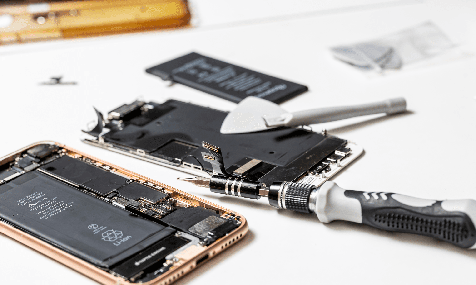 A close-up shot of a phone being repaired with tools in the foreground.